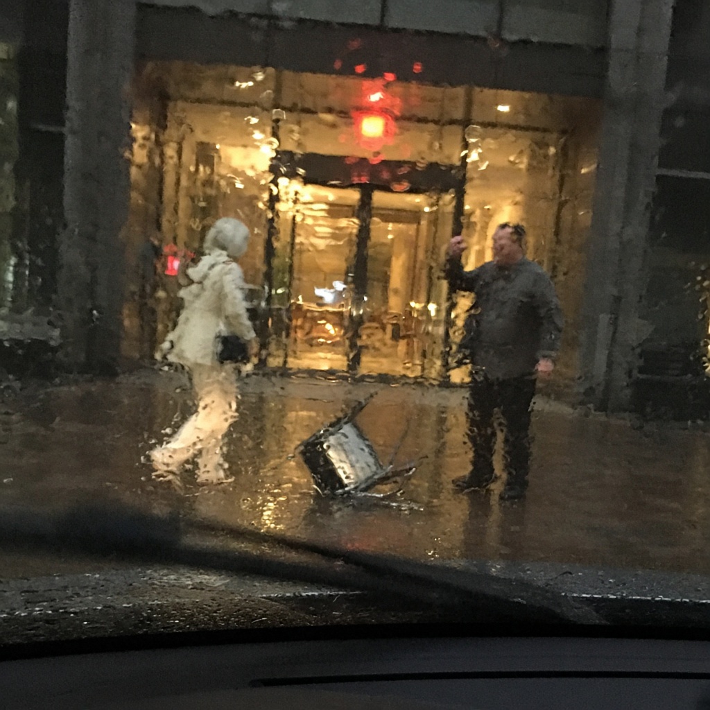 Scène de rue observée à travers un pare-brise sous la pluie